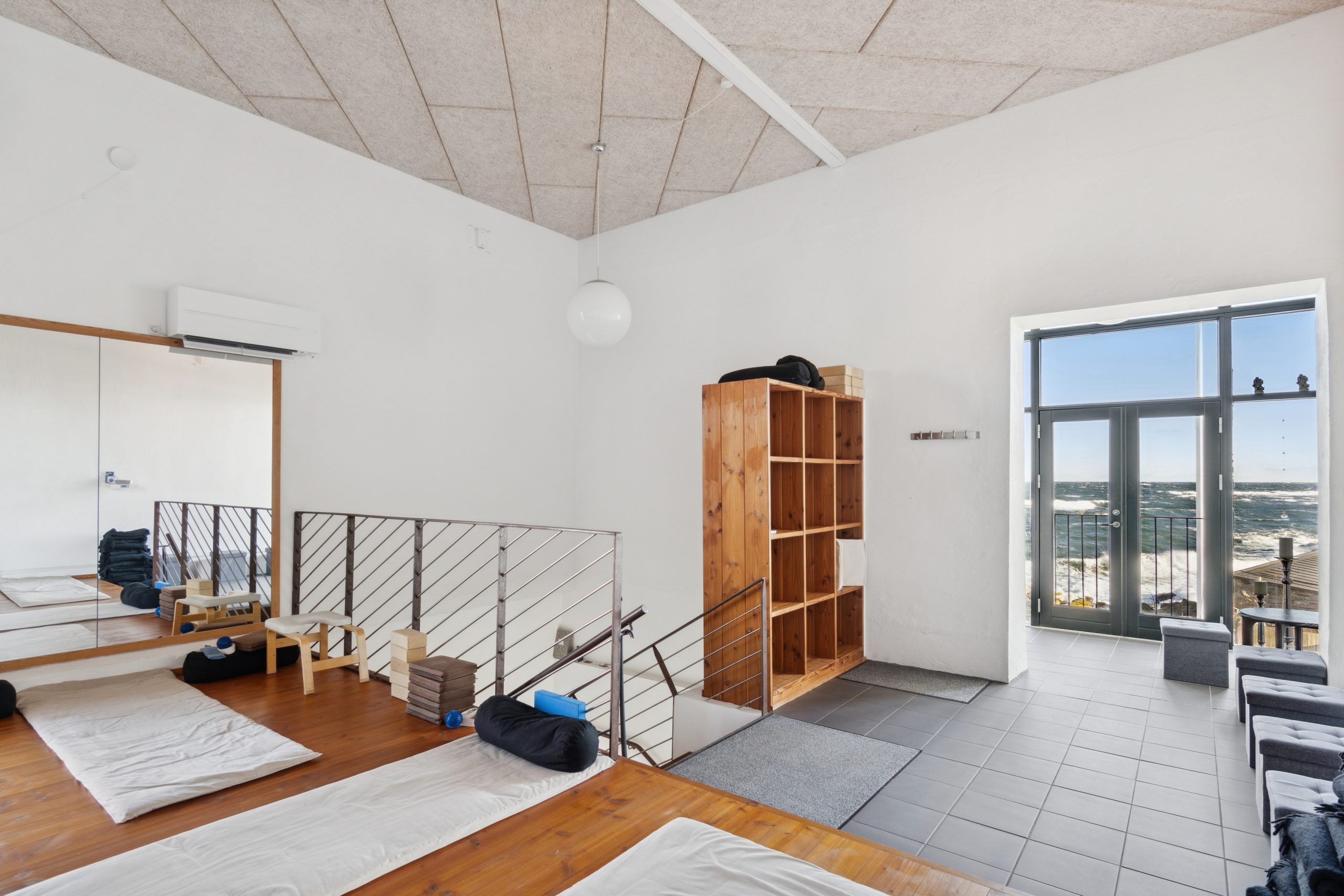 Indvendigt i yogastudiet med måtter, udstyr og havudsigt.