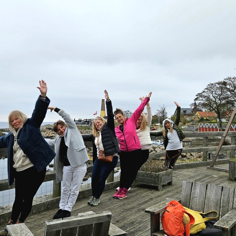 Gruppe i koordineret sidebøjning på trædæk ved havnen.
