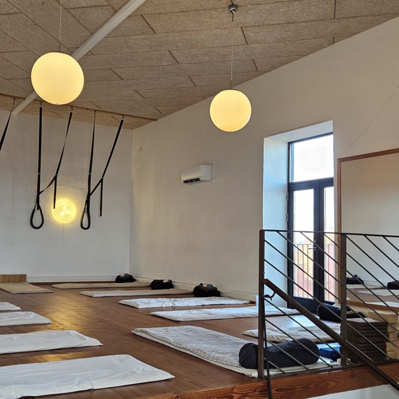 Yogarum forberedt med måtter, bolstre og varmt lys.