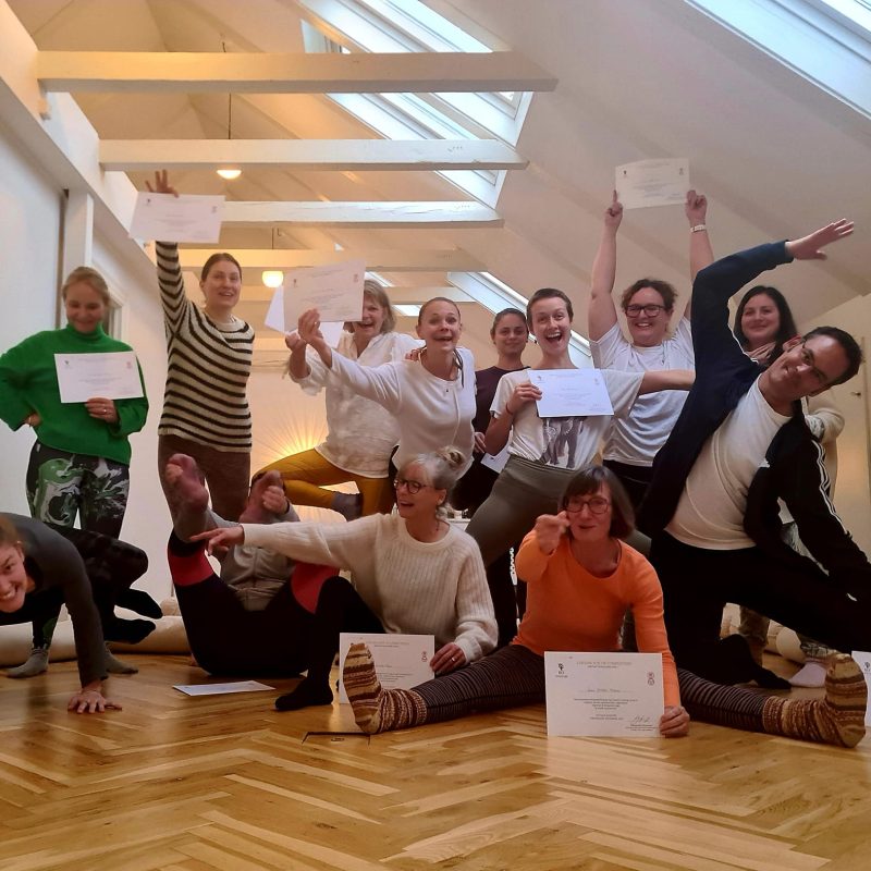 Feirende gruppe med certifikater efter yogaanatomi-uddannelse.